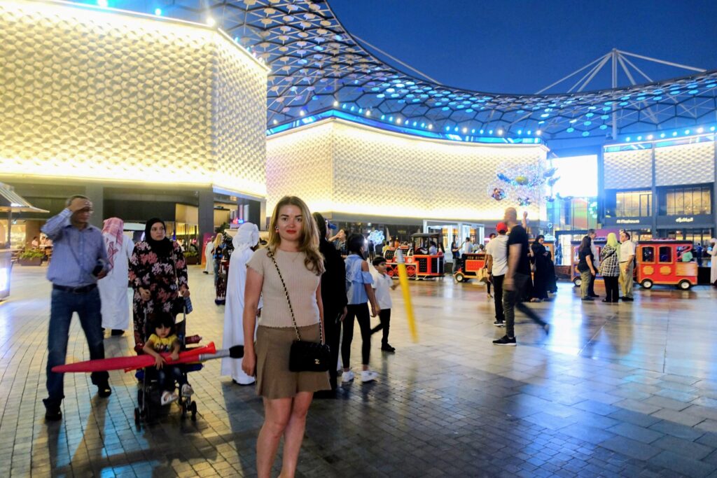 ドバイの煌びやかな屋外ショッピングモールに立つ女性