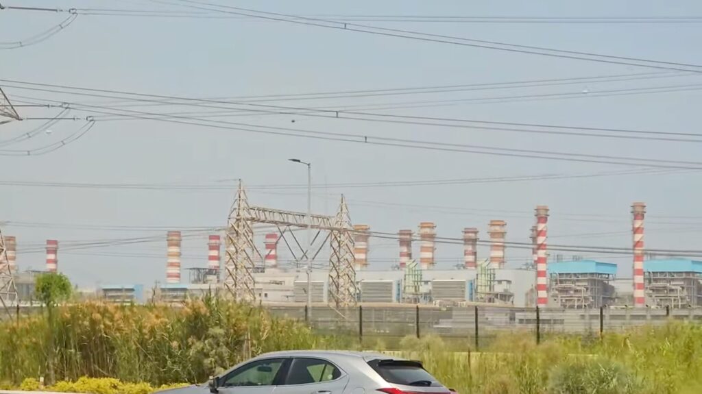 車窓から見た赤白の煙突が並ぶ発電・淡水化施設